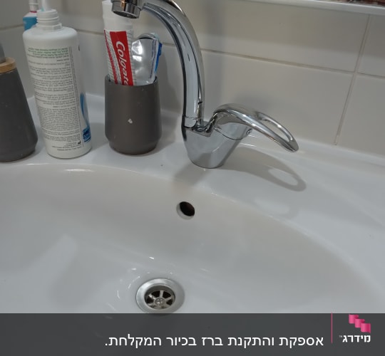 ברז כרום מעל כיור לבן עם ניקוז